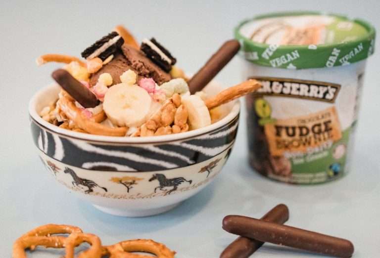 Ben Jerry's vegan fudge brownie next to a bowl full of ice cream and sweets