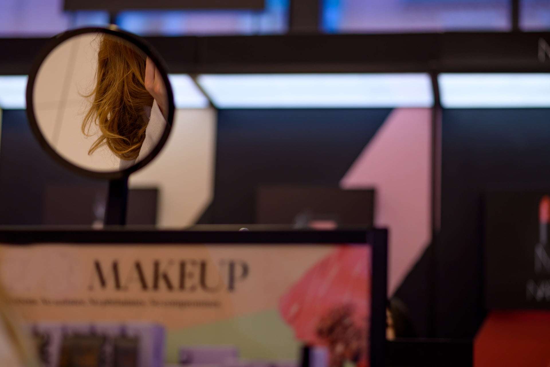 Woman in mirror applying makeup in department store