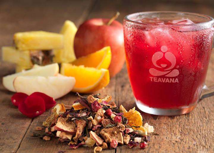 On a table dried fruits, oranges, apples and a glass of red teavana