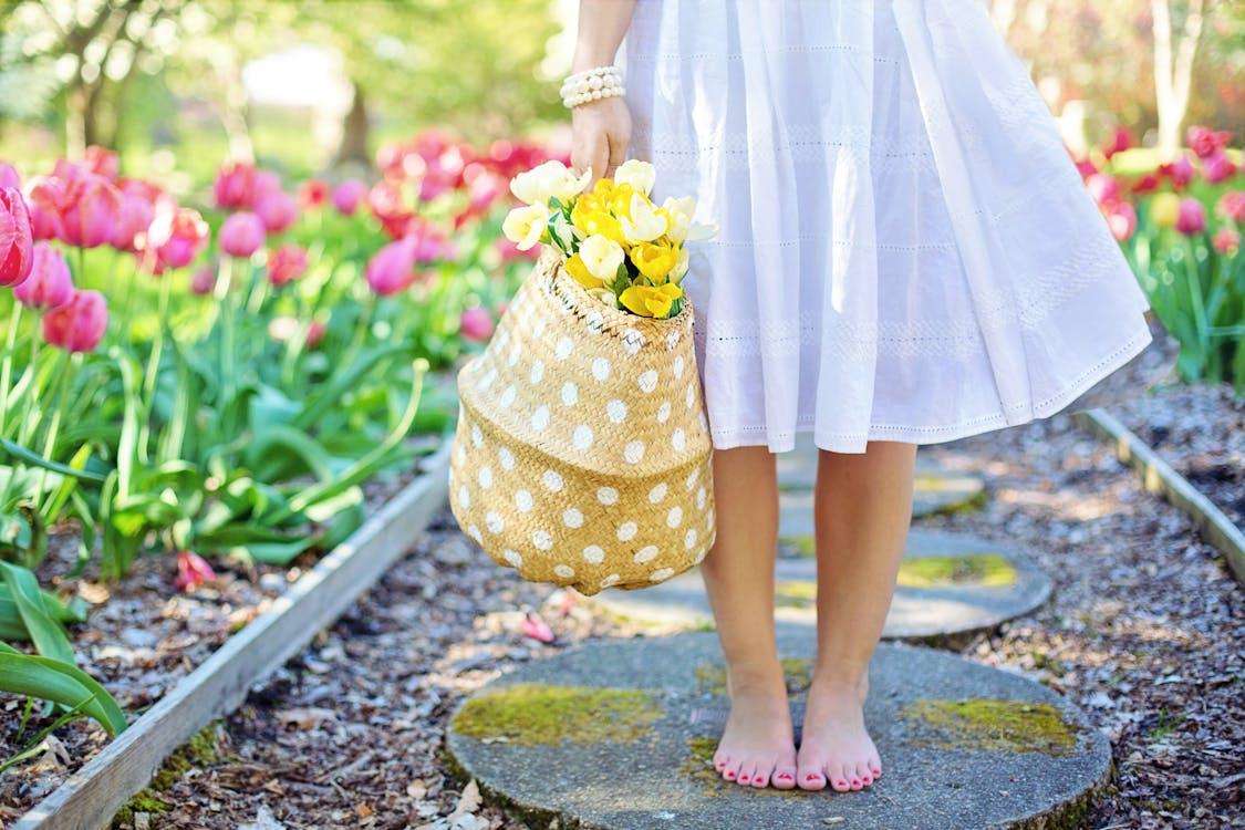 A girl or woman holding a bag with flowers in a beautiful garden with tulips