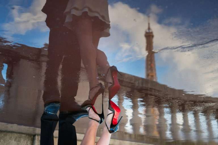 Louboutin heels and red soles at one of the Paris bridges with a reflection of the Eiffel tower