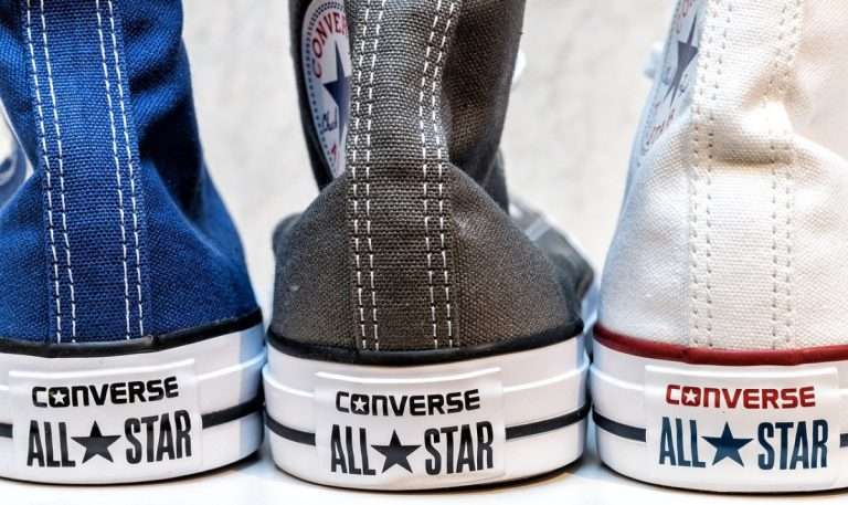 Three Converse sneakers in the colours blue, grey, and white. The classic high tops